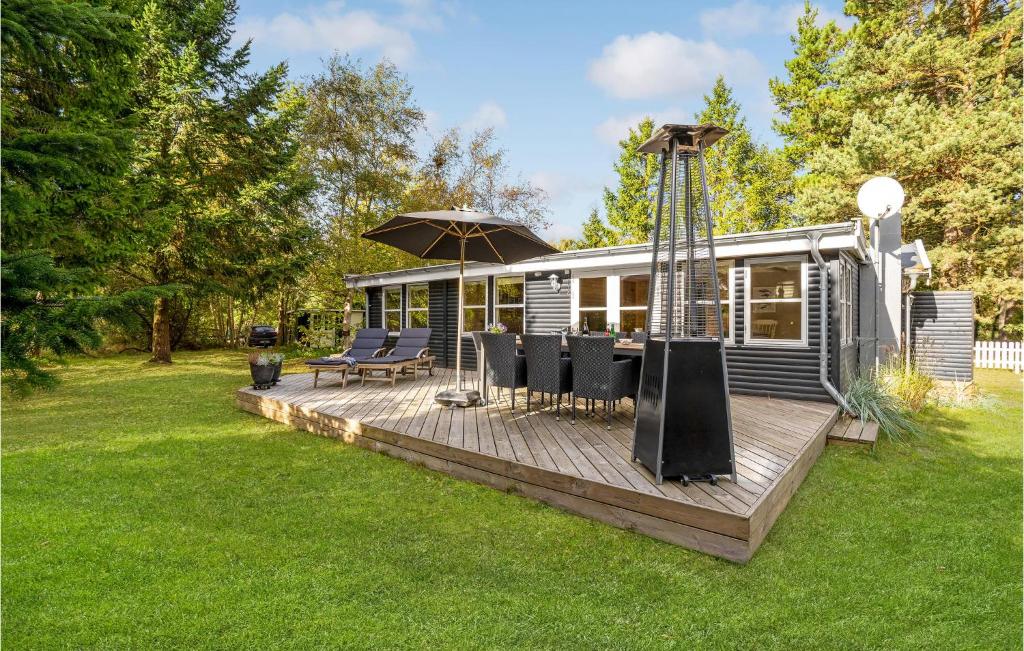 ein Mobilheim mit einer Terrasse mit Stühlen und einem Sonnenschirm in der Unterkunft Three-Bedroom Holiday Home In Vaggerlose in Bøtø By
