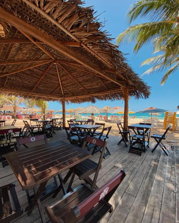 a beach with tables and chairs and a straw umbrella at iapôi Beira-Mar Maracaípe in Porto De Galinhas