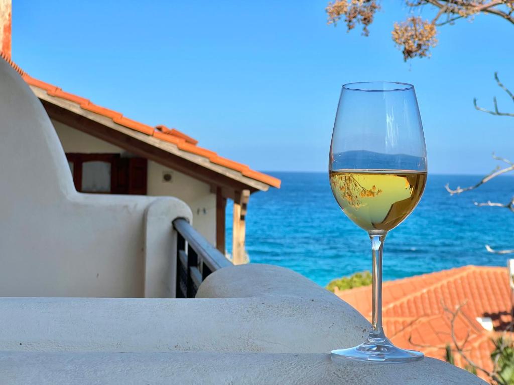 a glass of wine sitting on a table next to the ocean at Marinos Studios and Apartments in Gialiskari