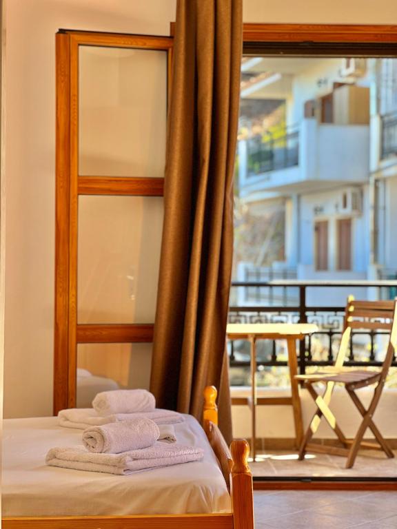 a bedroom with a bed and a balcony with a chair at Marinos Studios and Apartments in Gialiskari