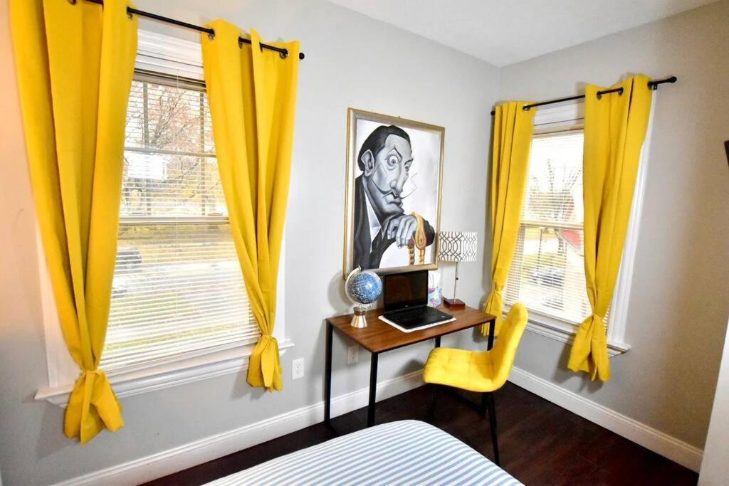 a bedroom with yellow curtains and a desk with a laptop at Lake Avenue Apartment in Cleveland