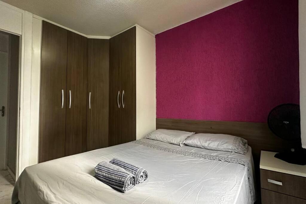 a bedroom with a large bed with a pink wall at Lindo Apto Térreo Relaxante com Garagem in São José dos Pinhais