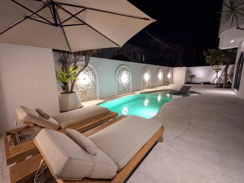a swimming pool with lounge chairs and an umbrella at Miko Villa Seminyak in Seminyak