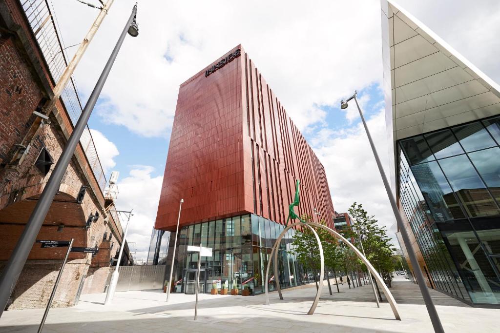 a tall red building with a sculpture in front of it at INNSiDE by Meliá Manchester in Manchester