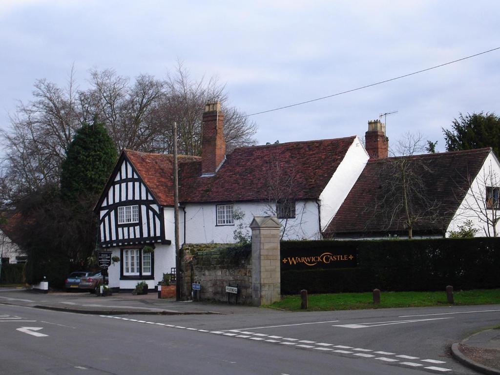 uma casa a preto e branco com um cartaz à frente. em Daisy Cottage em Warwick