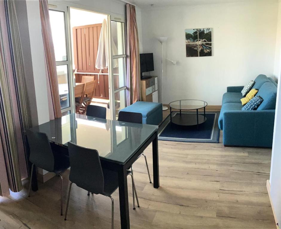- un salon avec une table en verre et un canapé bleu dans l'établissement Résidence le Village de Cap Esterel - maeva Home - Appartement 2 pièces 6 personnes - Prestige MAE-5674, à Saint-Raphaël