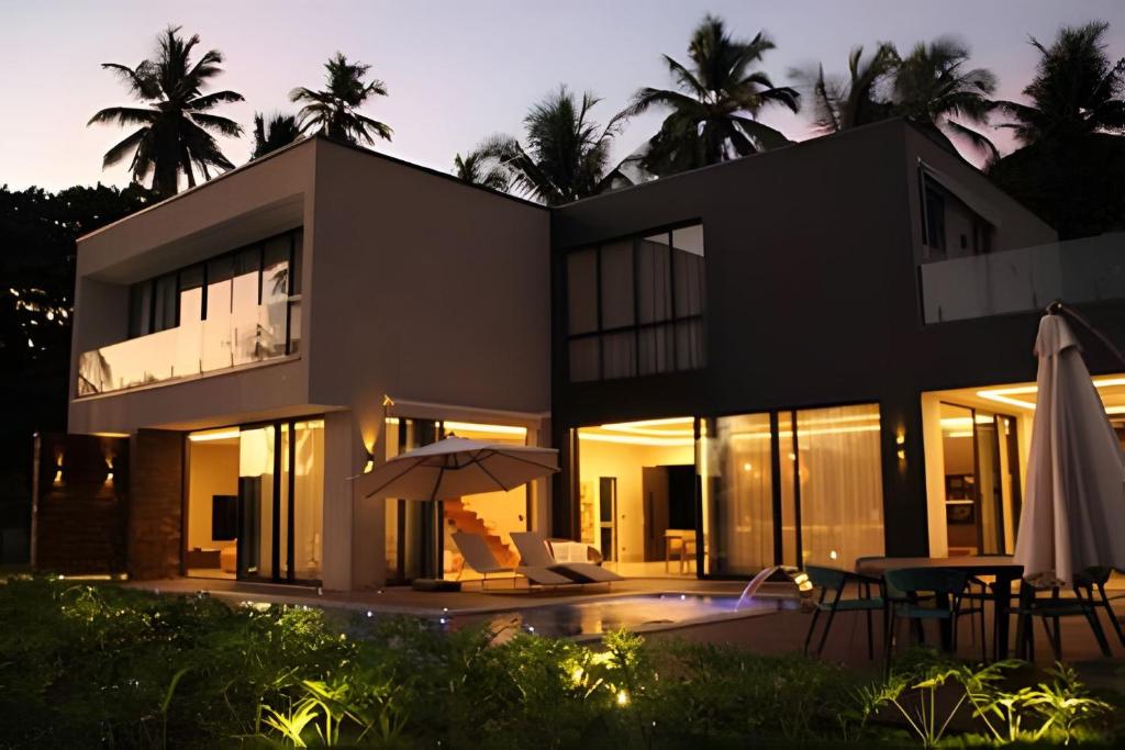 a black house with an umbrella and a table at Morro de São Paulo Casa 4° Praia de luxo in Cayru