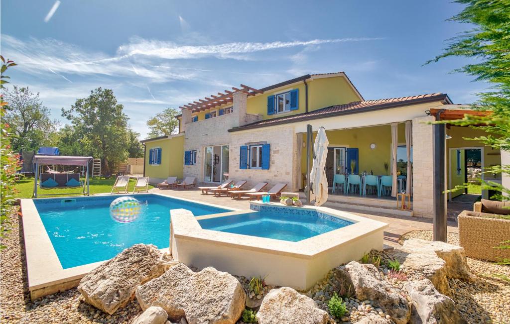une maison avec une piscine devant une maison dans l'établissement Pet Friendly Home In Naselje Muzini, à Tomišići