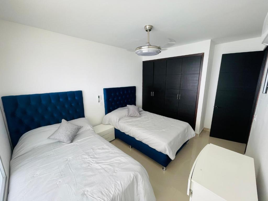 a bedroom with two beds and a blue headboard at Front beach apartment close to the Cartagena letters in Cartagena de Indias