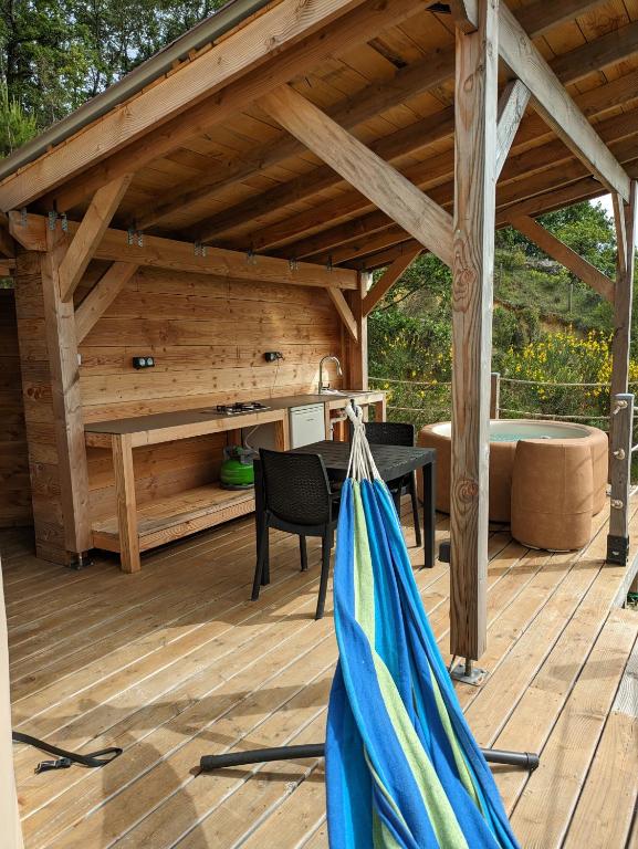 un patio en bois avec un hamac sur une terrasse en bois dans l'établissement Le dôme du Roc, à Belloc
