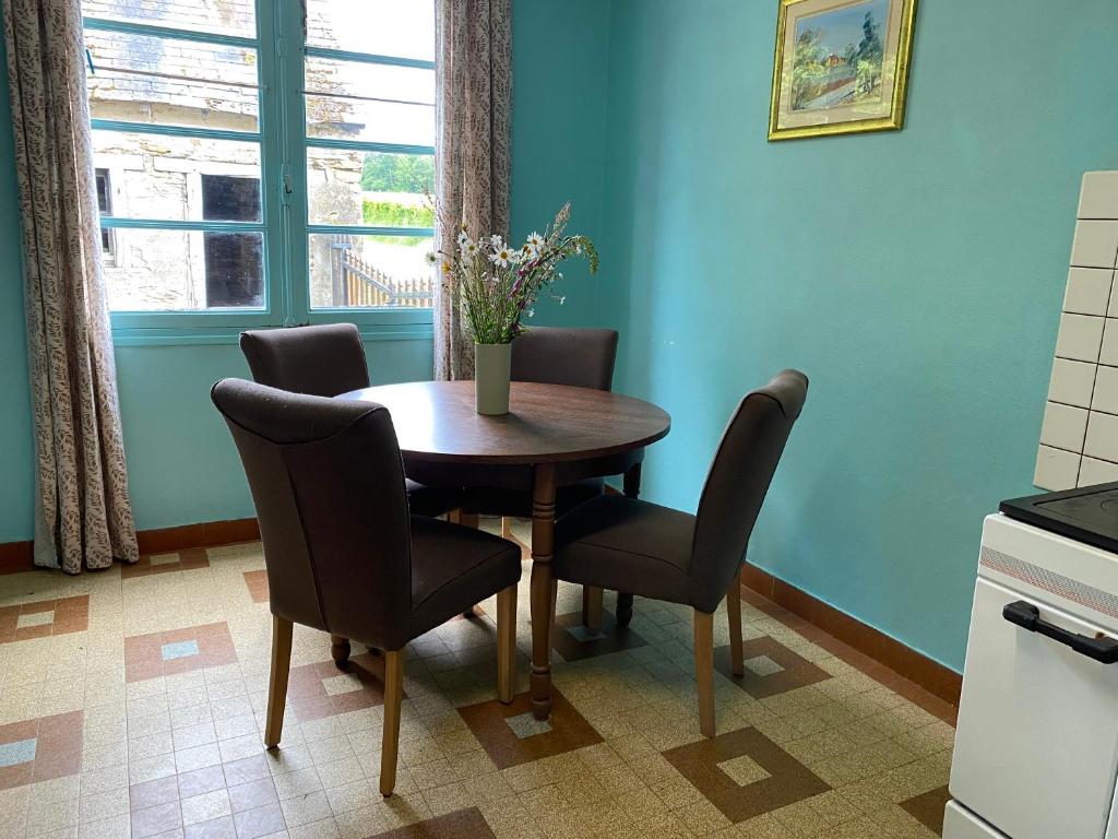 - une table à manger avec des chaises et un vase fleuri dans l'établissement Gite la Pomme de Pin bij boerderij, à Sazeray