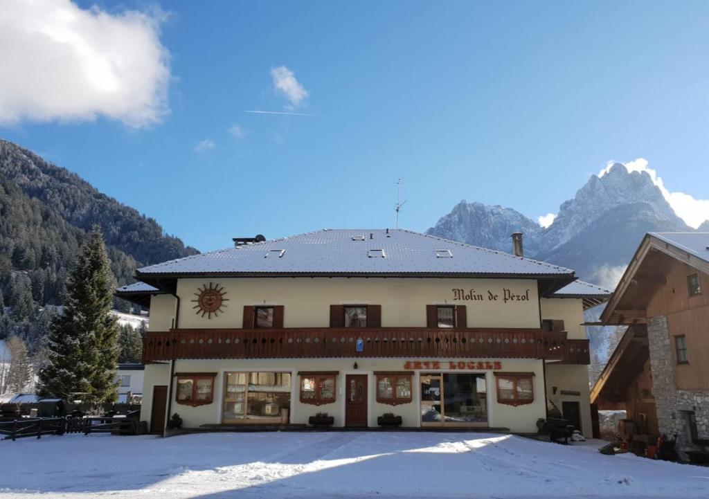 een gebouw in de bergen met sneeuw op de grond bij La Casa del Mulino in Pozza di Fassa