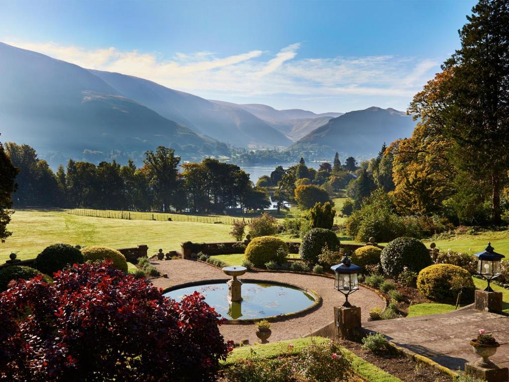 einen Garten mit einem Teich und Bergen im Hintergrund in der Unterkunft Macdonald Leeming House in Watermillock