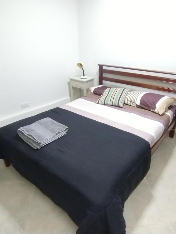 a bed with a blue and white blanket and a table at Depto Cabildo in San Salvador de Jujuy