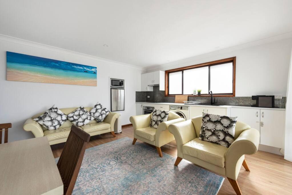 a living room with two couches and a kitchen at Waterfront and direct beach access with views in Ulladulla