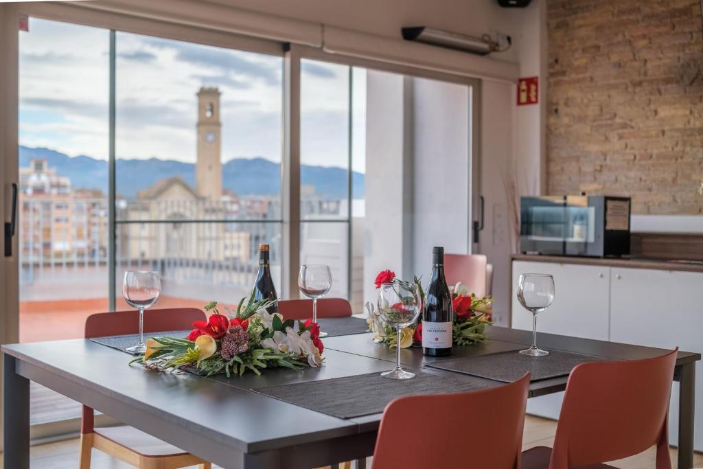 a dining room table with wine glasses and flowers on it at Àtic la Llotja in Tortosa