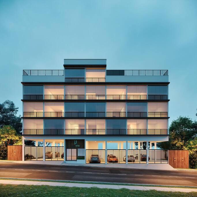 a tall building with cars parked in front of it at Studio lindo com ar condicionado e piscina - Bela Vita - 104 in São Lourenço