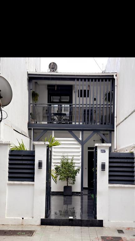 un edificio con balcone e porta con una pianta di CYRUS Hôtel -Housse cœur de ville a Pointe-à-Pitre