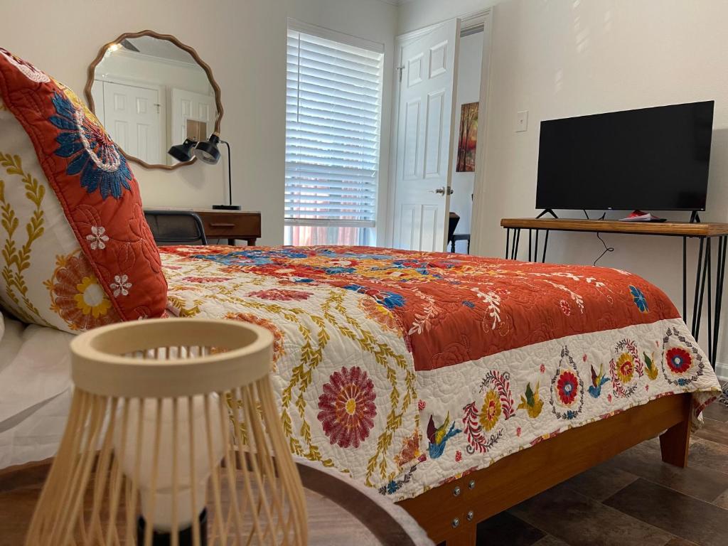 ein Schlafzimmer mit einem Bett mit einer bunten Bettdecke und einem TV in der Unterkunft Cozy Condo in Lake Charles