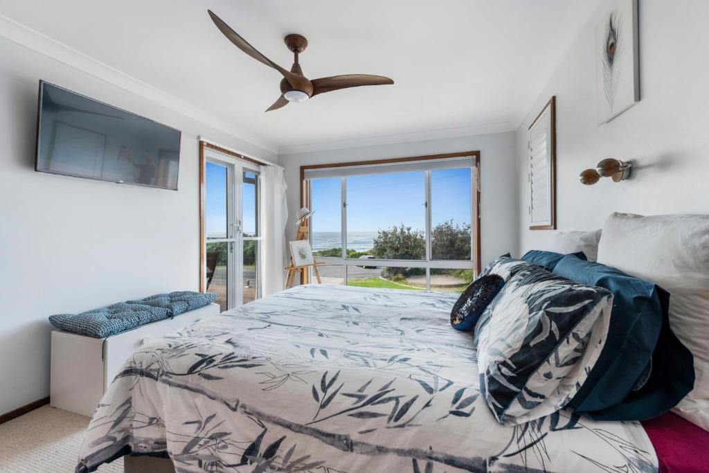 a bedroom with a bed and a ceiling fan at Waterfront and direct beach access with views in Ulladulla