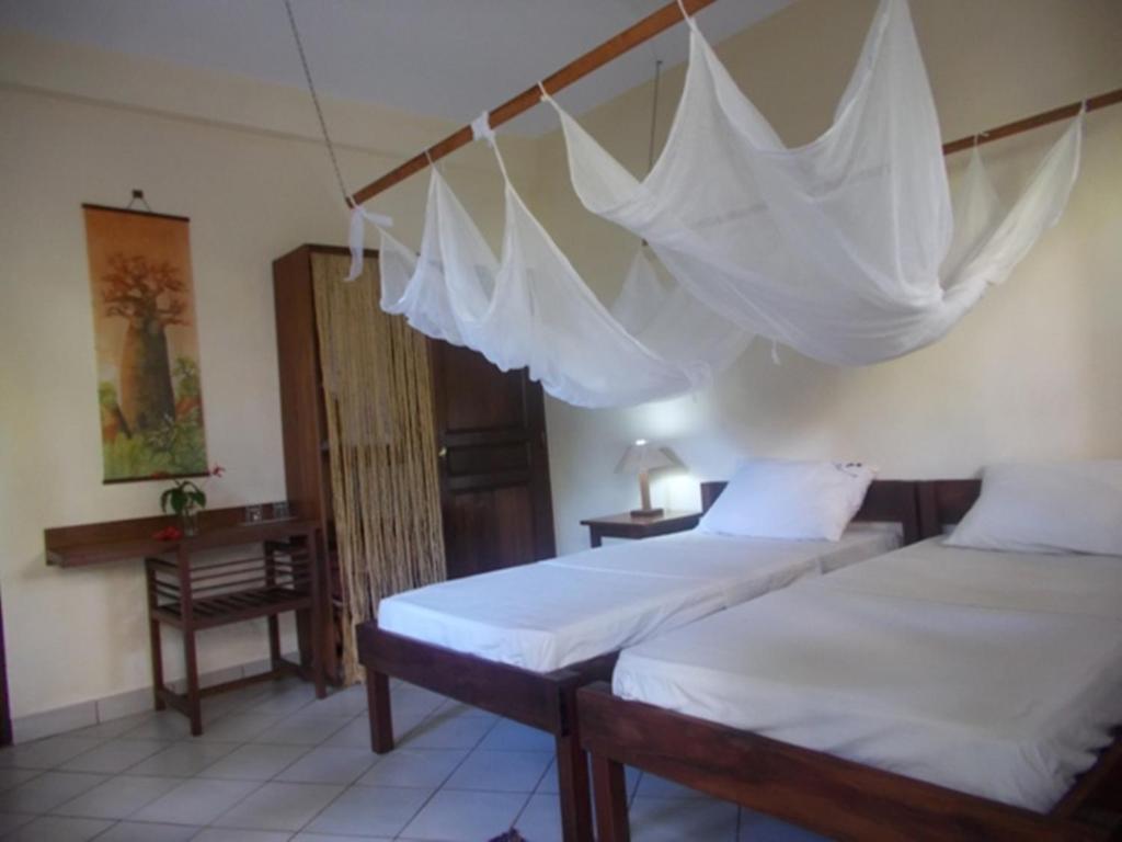2 Betten in einem Zimmer mit an der Wand hängenden Netzen in der Unterkunft L' Hippocampe in Maroantsetra