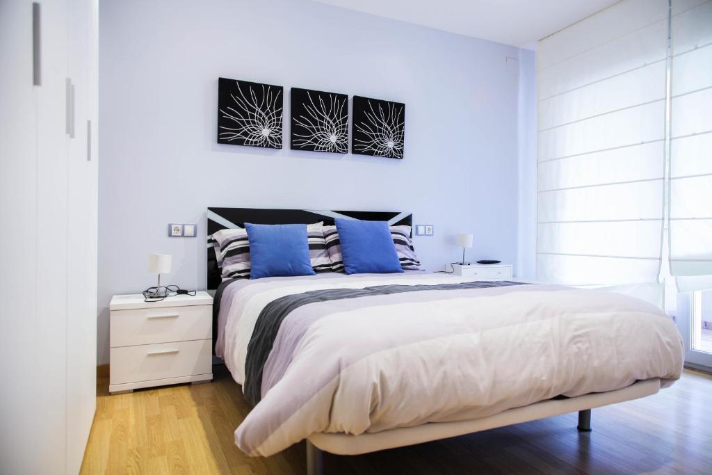a white bedroom with a large bed with blue pillows at El Bon Pas Rural in Boldú