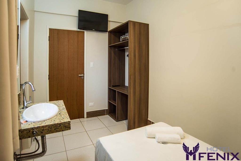 W łazience znajduje się umywalka, toaleta i lustro. w obiekcie Hotel Fenix w mieście Assis