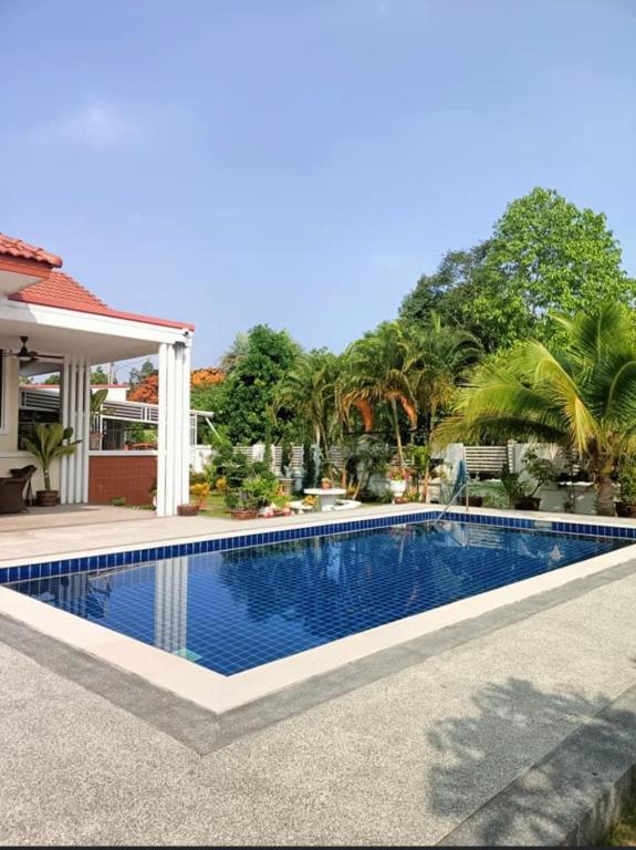 a swimming pool in front of a house at Nongnuchs Homestay Two Single Beds in San Sai