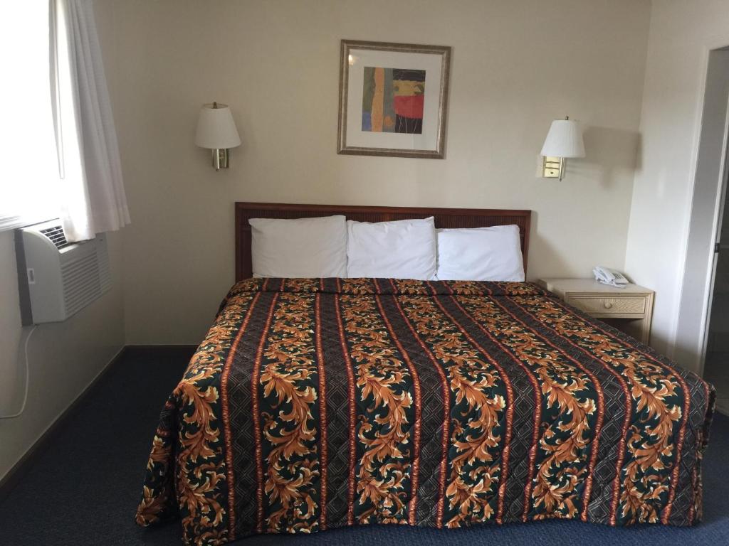 a hotel room with a bed with a blanket at Coastal Motel in Jacksonville