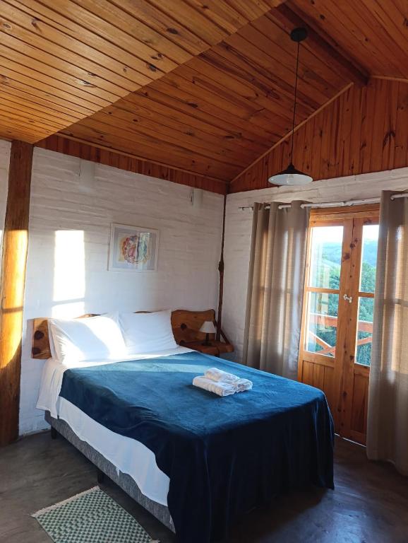 a bedroom with a large bed with a blue blanket at Solar dos Pinhais in Santo Antônio do Pinhal