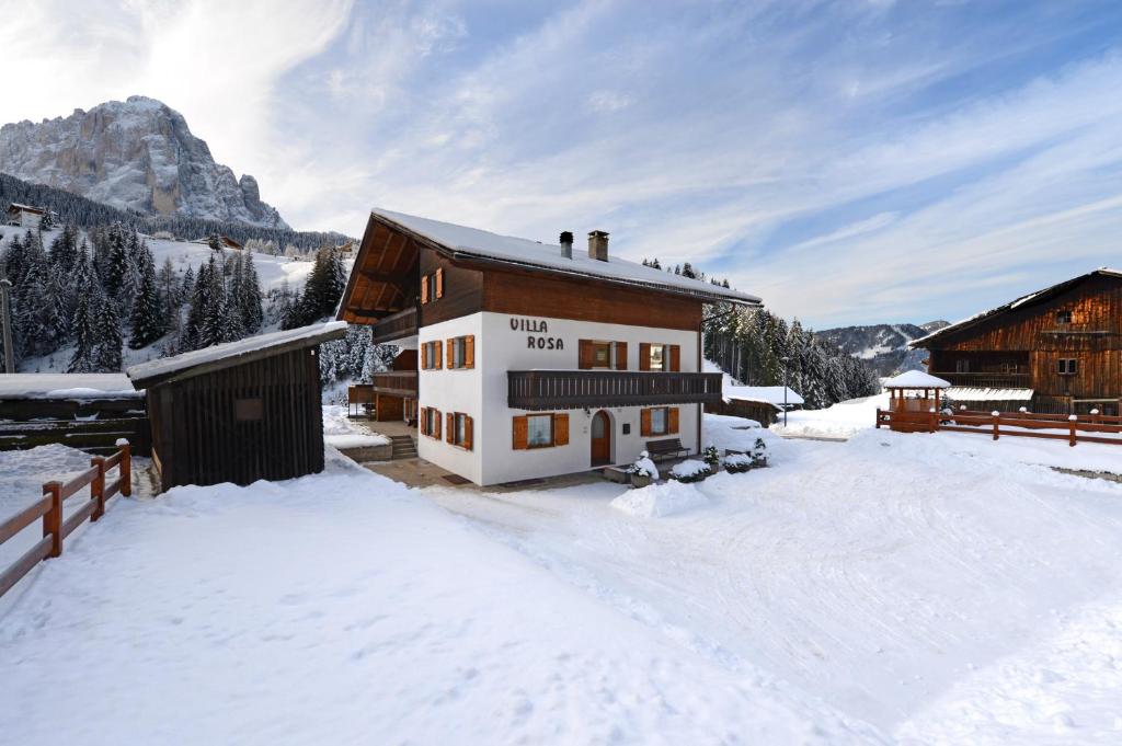 a house in the snow with a mountain at Apartments Villa Rosa in Selva di Val Gardena