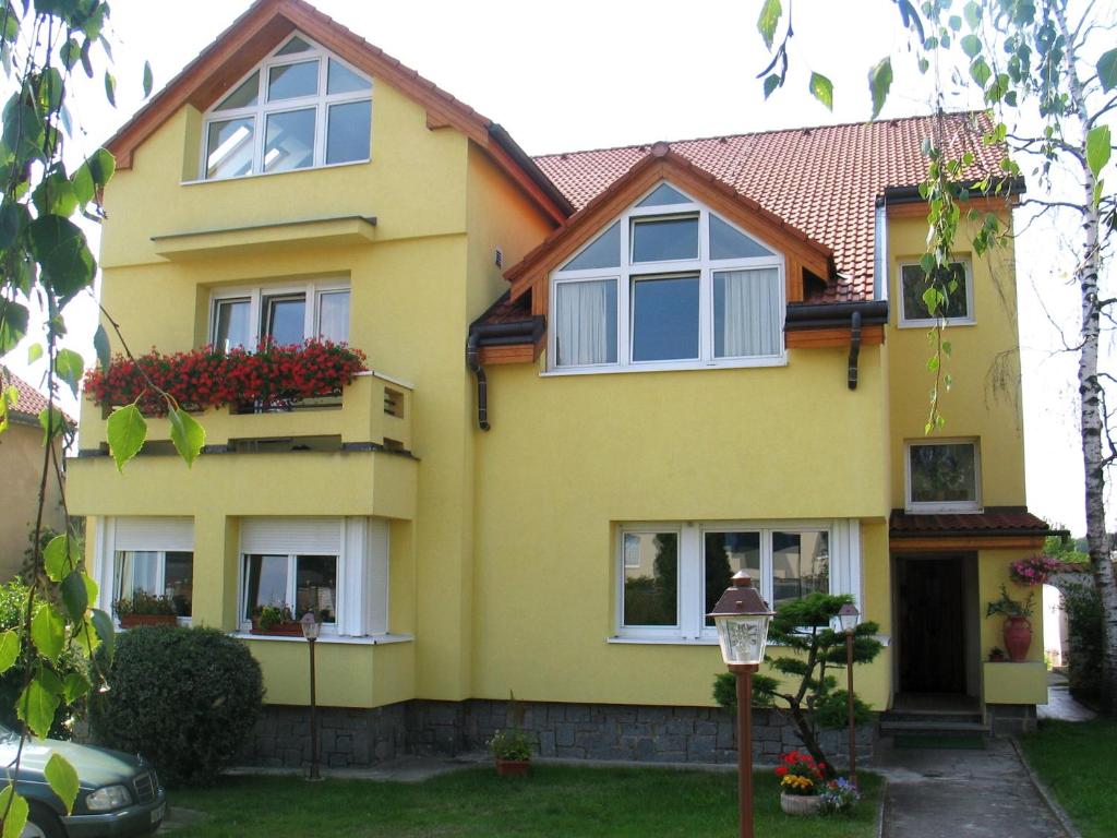 une maison jaune avec des fleurs dans les fenêtres dans l'établissement Fontána, à Prague