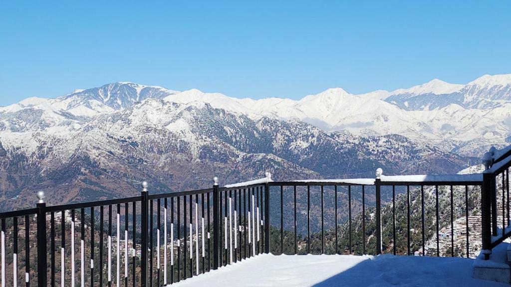 a black fence with snow covered mountains in the background at HILL MOUNT Cabin Home in Chamba