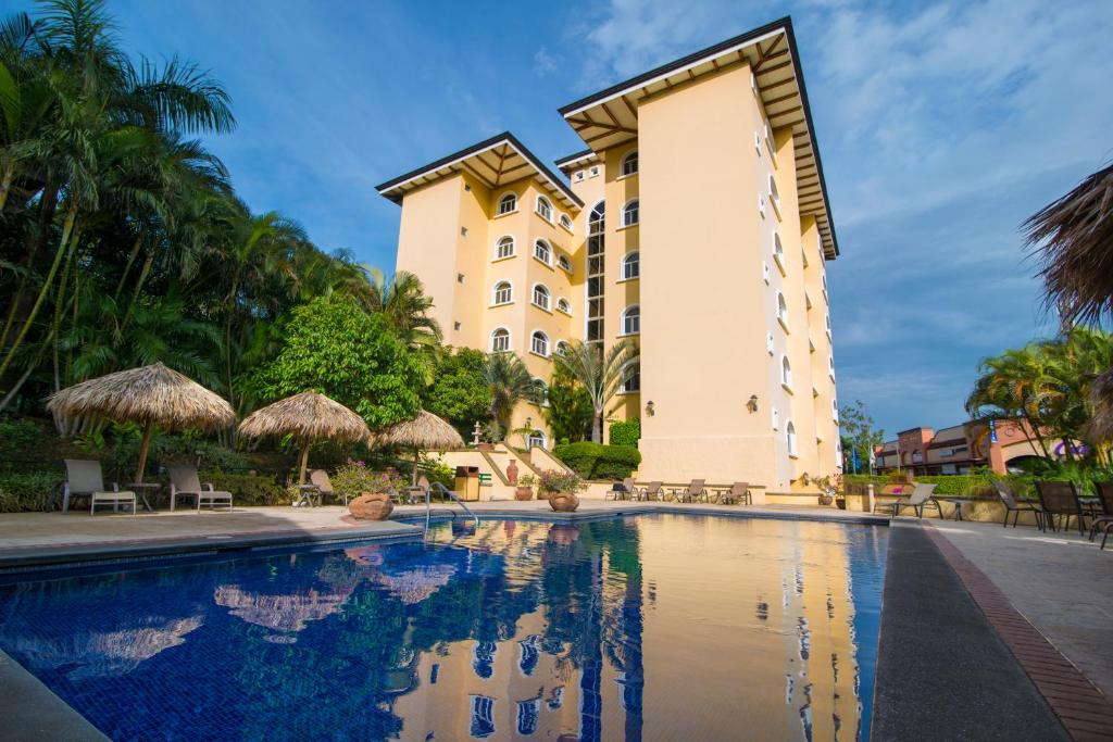 a hotel with a swimming pool in front of a building at Apartotel & Suites Villas del Rio in San José