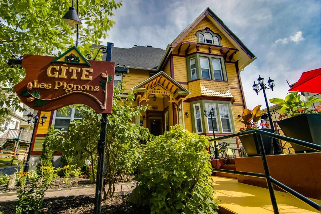 a yellow house with a sign in front of it at Gîte Les Pignons in Saint-Damien