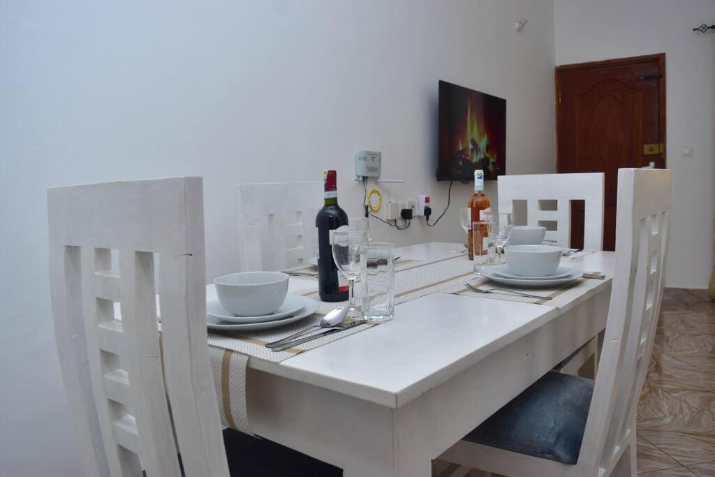 a white dining room table with a bottle of wine at Taji Two bedroom lovely apartment in Malindi