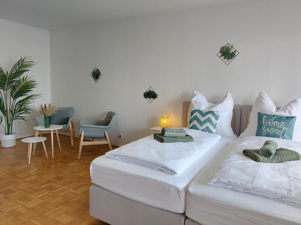 a room with two beds and a table and chairs at Rooftop Apartments - Gemütliches Apartment 4P nahe Ratiopharm Arena in Neu Ulm