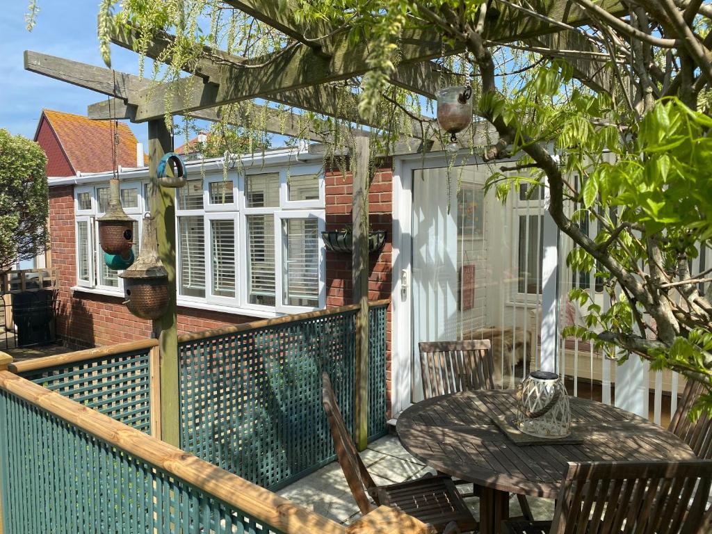 a patio with a table and chairs on a balcony at Shoreline hideaway - next to the beach in Little Holland