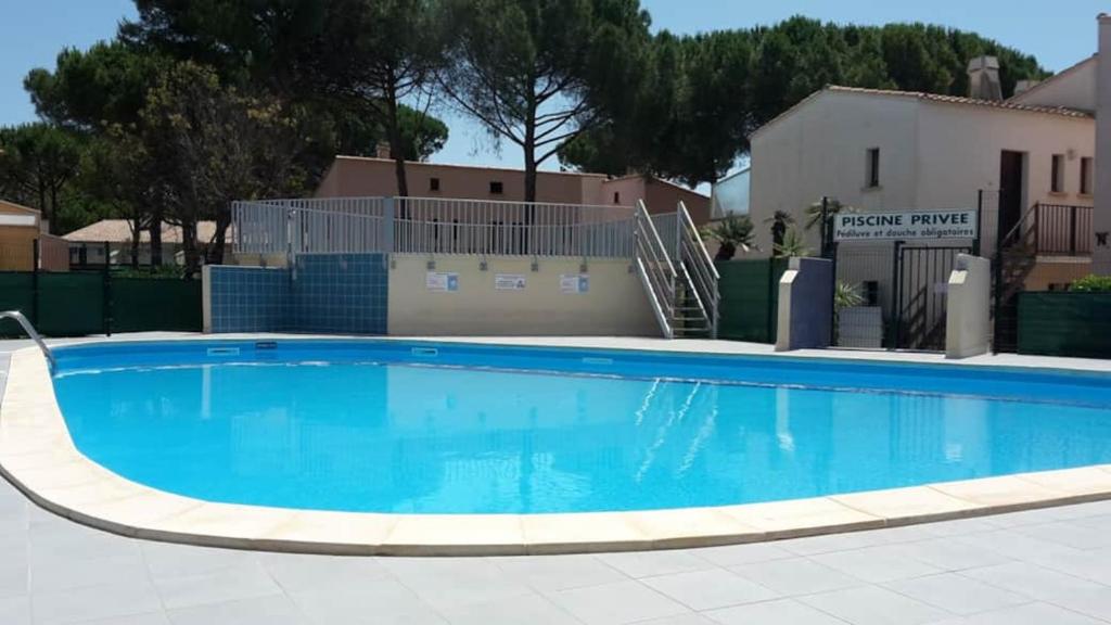 une grande piscine bleue devant un immeuble dans l'établissement Résidence Euréka H137, au Cap d'Agde