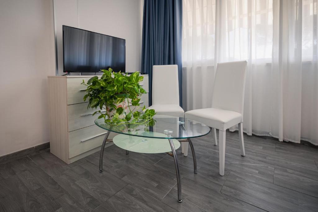 a living room with a glass table and a tv at Hotel Giulietta e Romeo in Casal Palocco