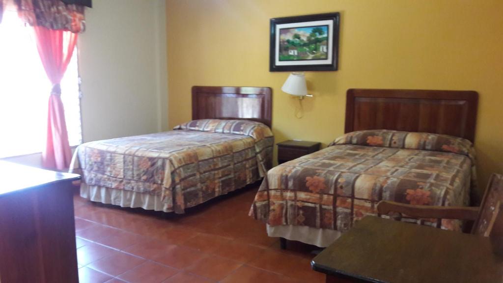 a hotel room with two beds and a table at Hotel Brisas de Copan in Copán Ruinas