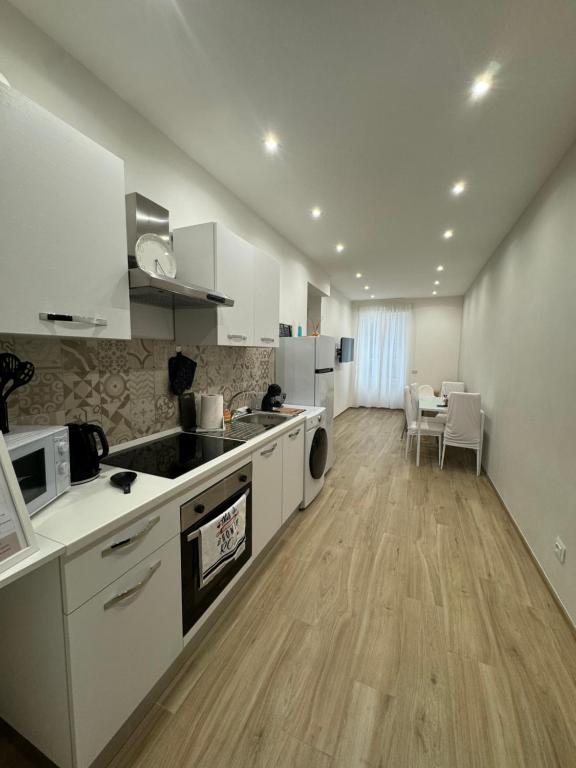 a large kitchen with white cabinets and a table at Dimora Appia in Rome