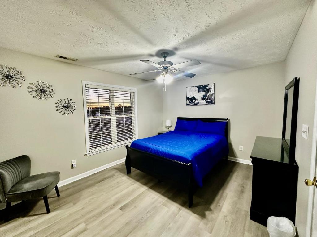 a bedroom with a blue bed and a chair at Haven Away From Home Ideal For Long Term Stays in Fayetteville