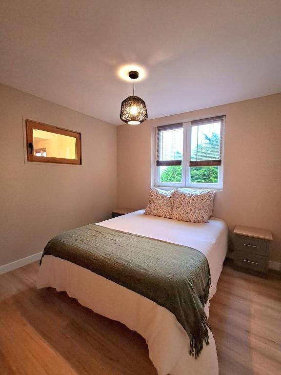 a bedroom with a bed and two windows at Chalet de Lanvaux in Saint-Jean-Brévelay