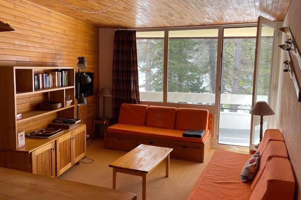 - un salon avec un canapé orange et des fenêtres dans l'établissement T3 aux Ecrins IV, skis aux pieds à Vars, à Vars