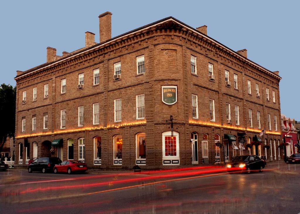 un gran edificio de ladrillo con coches estacionados frente a él en Baldachin Inn, en Merrickville