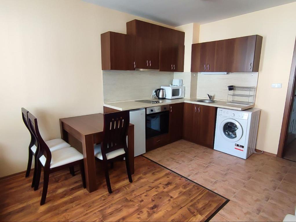 a small kitchen with a table and a washing machine at "Mountain Dream" Apartments 200m from Ski Road in Bansko