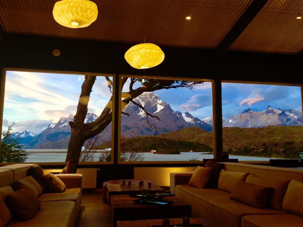uma sala de estar com uma grande janela com vista para as montanhas em Hotel Lago Grey em Torres del Paine