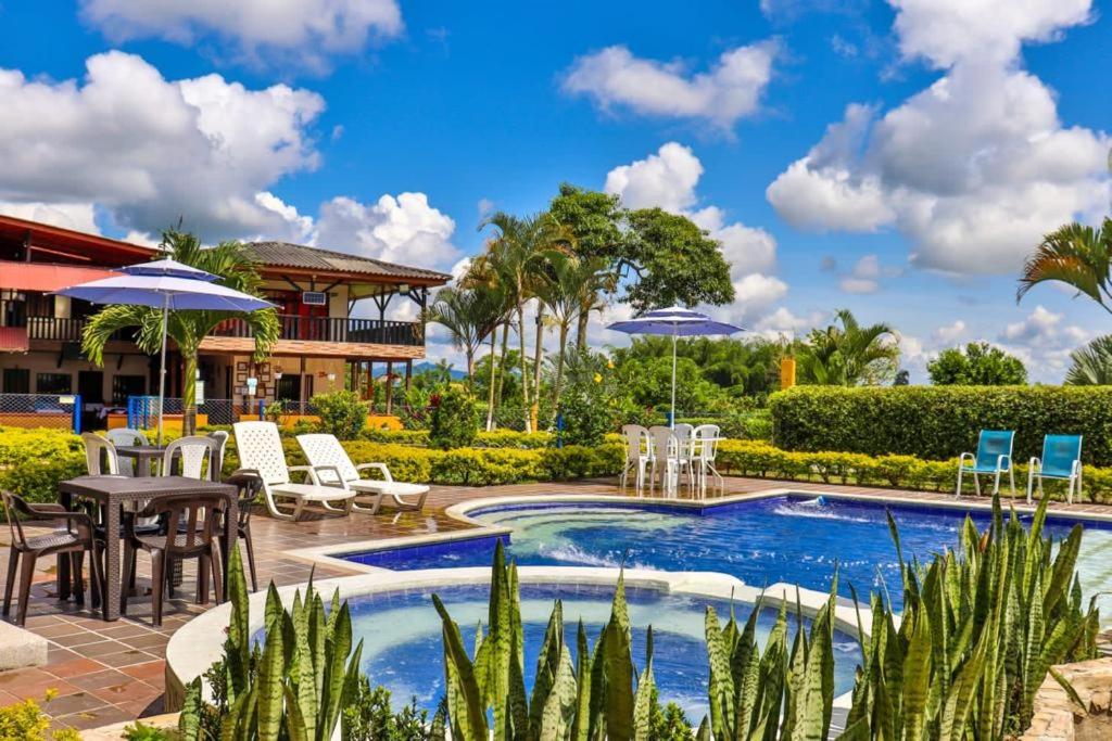 a resort pool with chairs and tables and umbrellas at Finca Hotel los Alpes in Quimbaya