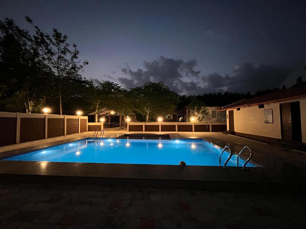 a swimming pool in a yard at night at Ammara Eco Stays in Avathi